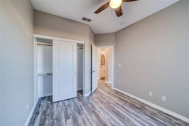 unfurnished bedroom featuring light wood-type flooring, a closet, visible vents, and baseboards