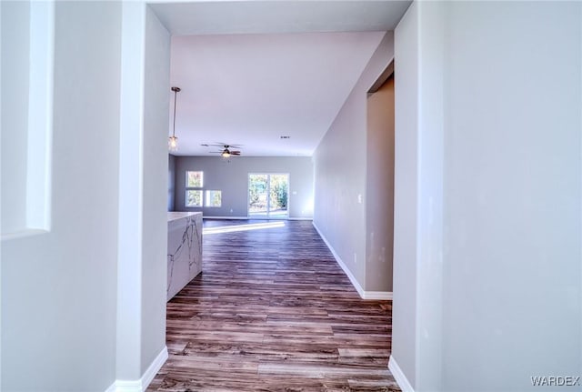 corridor with baseboards and wood finished floors