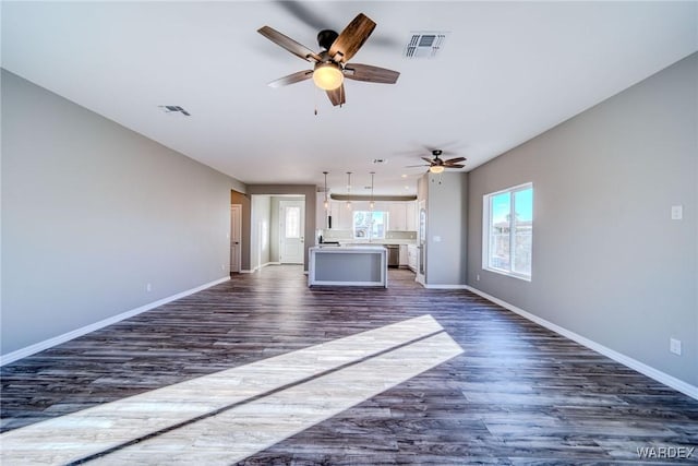 unfurnished living room featuring dark wood-type flooring, visible vents, and baseboards