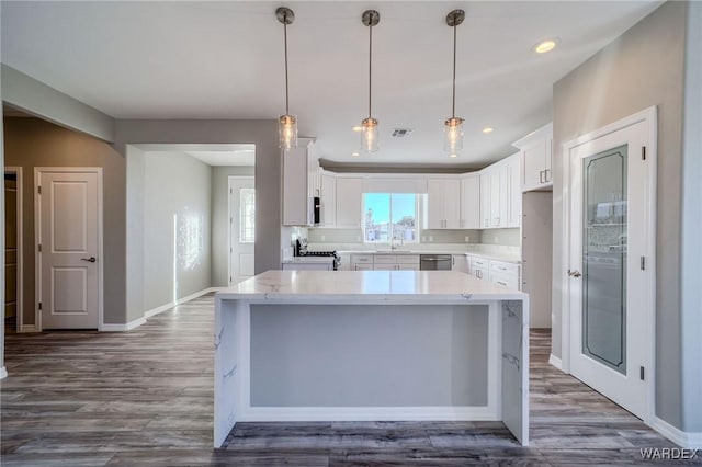 kitchen featuring visible vents, dishwasher, a center island, hanging light fixtures, and white cabinetry