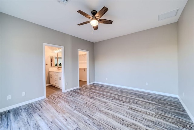 unfurnished bedroom with light wood finished floors, a closet, visible vents, a spacious closet, and baseboards