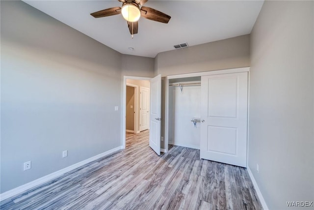 unfurnished bedroom featuring baseboards, visible vents, ceiling fan, light wood-type flooring, and a closet