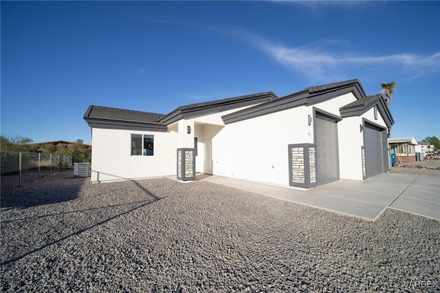 rear view of house featuring fence, an attached garage, and stucco siding