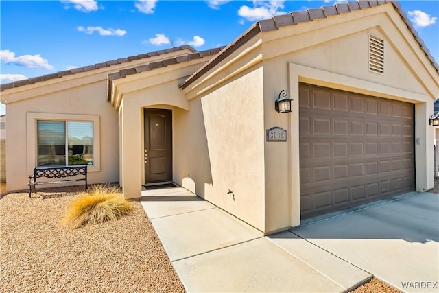 view of front of house featuring a tile roof, an attached garage, driveway, and stucco siding