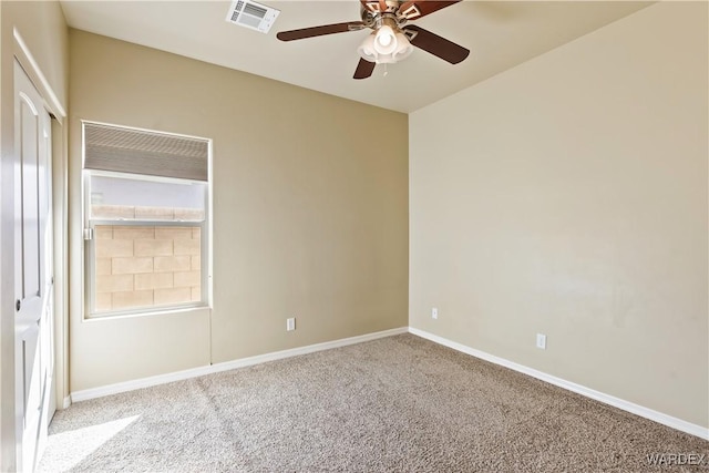 carpeted spare room featuring a ceiling fan, visible vents, and baseboards