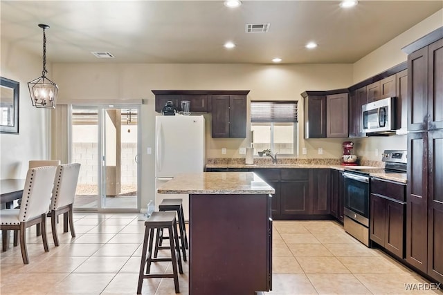 kitchen with visible vents, a center island, light tile patterned floors, stainless steel appliances, and a sink