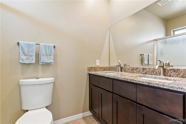 bathroom featuring double vanity, visible vents, toilet, and a sink