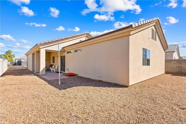 back of house featuring stucco siding, a patio, and a fenced backyard