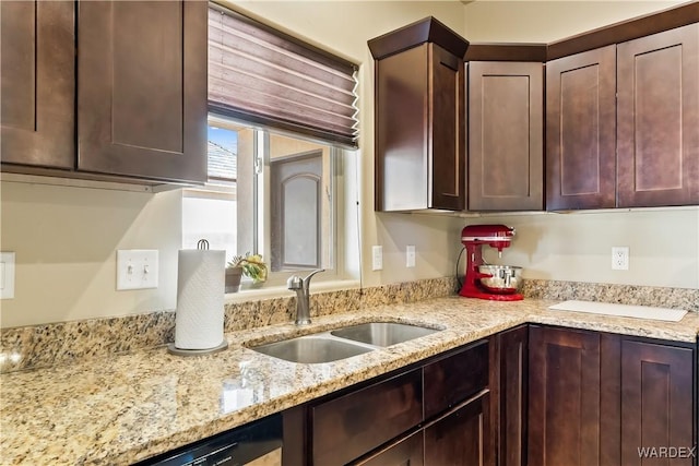 kitchen featuring dark brown cabinets, light stone countertops, and a sink