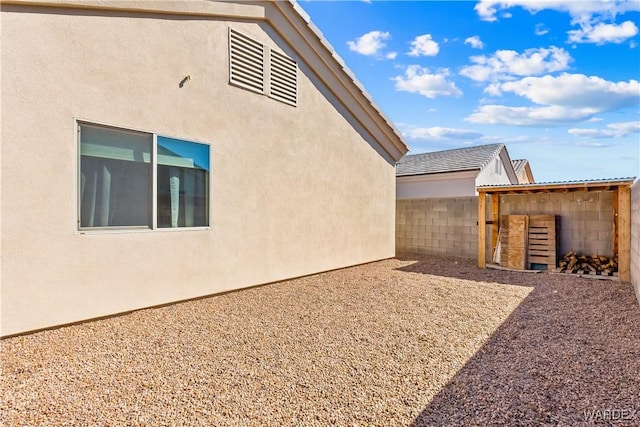 view of side of property with stucco siding, an outdoor structure, and fence