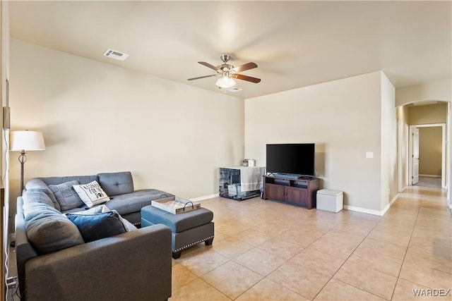 living room with light tile patterned floors, visible vents, arched walkways, and ceiling fan