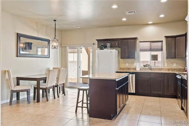 kitchen featuring visible vents, a sink, a kitchen island, freestanding refrigerator, and dishwasher