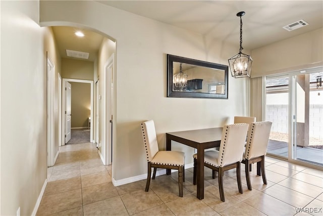 dining room with light tile patterned floors, visible vents, arched walkways, and a chandelier