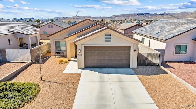 view of front of property with an attached garage, fence, stucco siding, driveway, and a mountain view