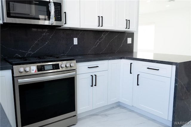 kitchen with marble finish floor, appliances with stainless steel finishes, white cabinetry, and decorative backsplash