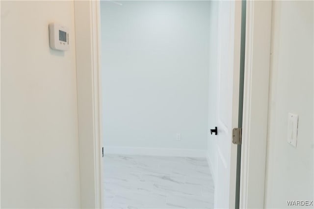 corridor featuring marble finish floor and baseboards