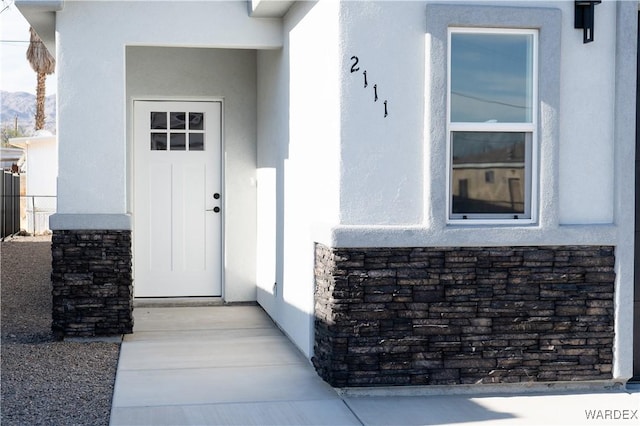 view of exterior entry with stone siding and stucco siding