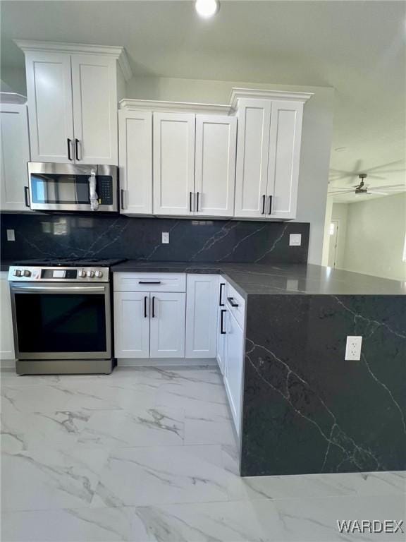 kitchen with marble finish floor, appliances with stainless steel finishes, backsplash, and white cabinetry