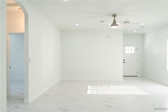 empty room with marble finish floor, visible vents, arched walkways, and recessed lighting