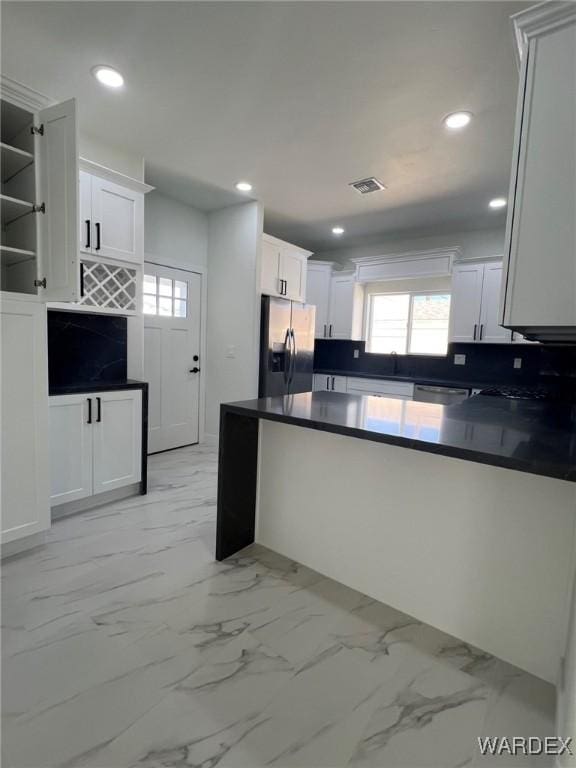 kitchen featuring marble finish floor, stainless steel appliances, dark countertops, visible vents, and white cabinetry