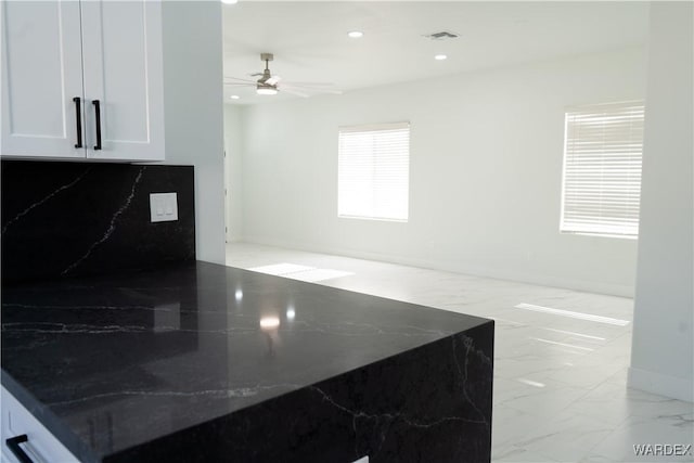 kitchen with marble finish floor, tasteful backsplash, recessed lighting, white cabinetry, and dark stone countertops