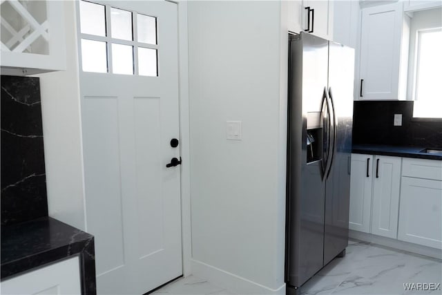 kitchen with white cabinets, marble finish floor, tasteful backsplash, dark stone countertops, and stainless steel fridge