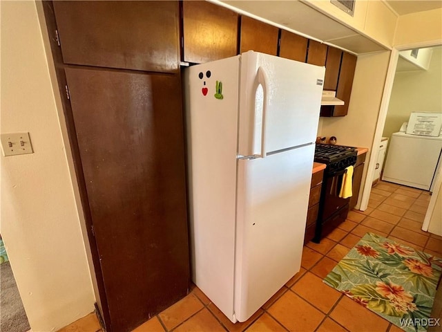 kitchen featuring under cabinet range hood, light countertops, freestanding refrigerator, washer / clothes dryer, and gas stove