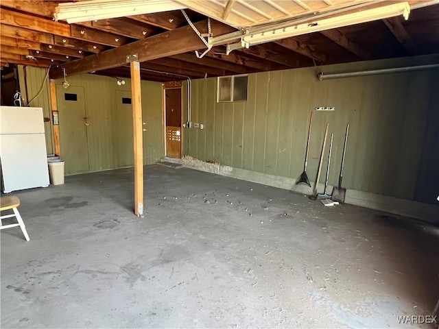 basement with freestanding refrigerator and wood walls