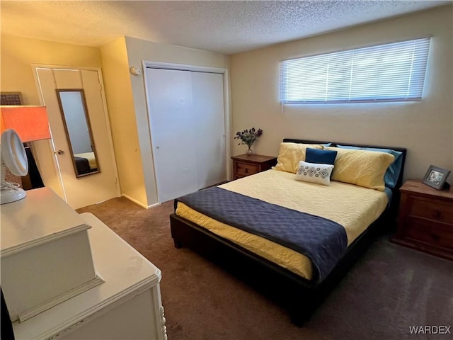 bedroom with a textured ceiling, dark colored carpet, and a closet