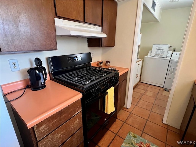 kitchen with washer and clothes dryer, light tile patterned floors, visible vents, black gas range oven, and under cabinet range hood