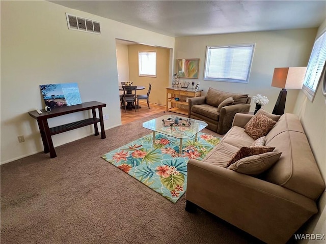 living area with carpet floors, visible vents, and baseboards