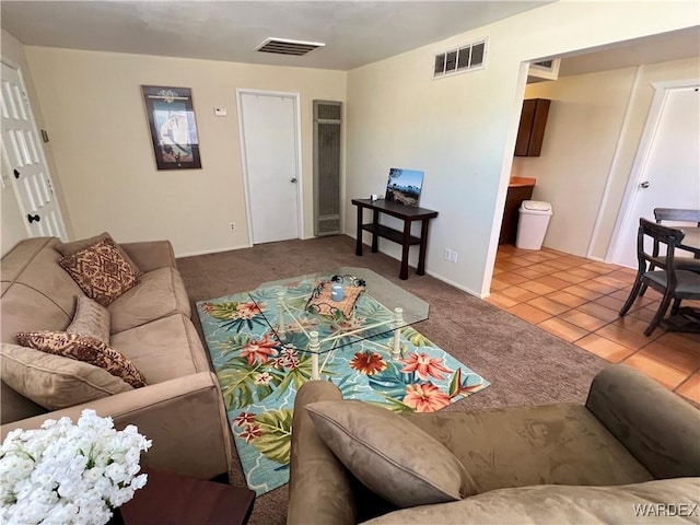 living area featuring light tile patterned flooring, visible vents, and light colored carpet