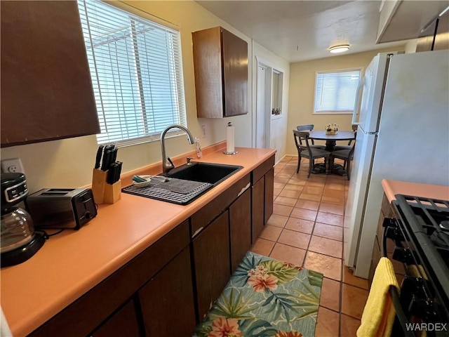 kitchen with light tile patterned floors, light countertops, a sink, and dark brown cabinetry