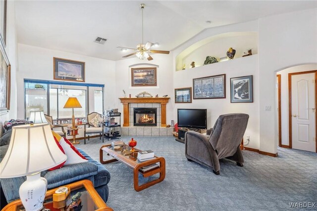 carpeted living room featuring arched walkways, high vaulted ceiling, a fireplace, and visible vents