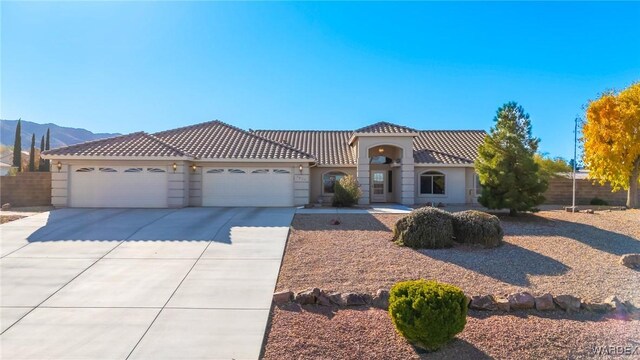 mediterranean / spanish-style home featuring a mountain view, a garage, a tile roof, concrete driveway, and stucco siding