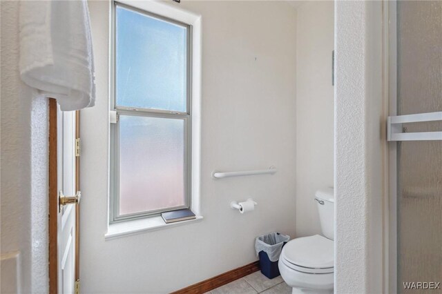 bathroom featuring a wealth of natural light, baseboards, tile patterned flooring, and toilet