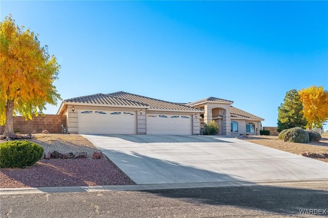 mediterranean / spanish house with concrete driveway, an attached garage, a tiled roof, and stucco siding