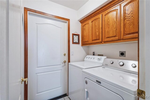 clothes washing area with washing machine and dryer and cabinet space