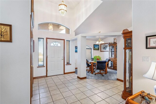 entryway with a chandelier, a wealth of natural light, and light tile patterned flooring