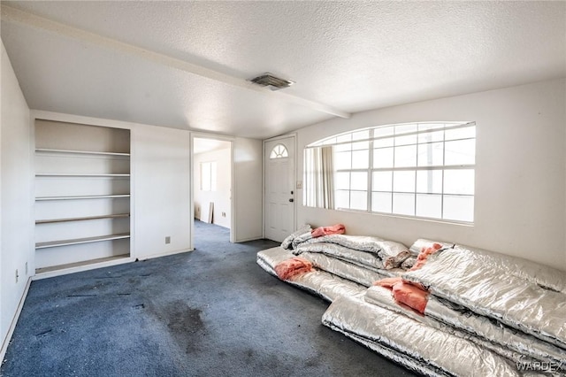 bedroom with dark colored carpet, visible vents, and a textured ceiling