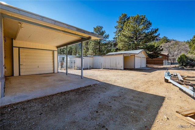 view of yard with a garage, fence, and an outbuilding