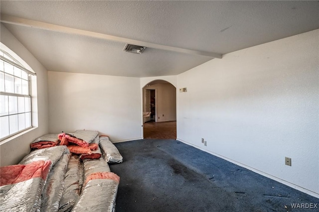 interior space with arched walkways, a textured ceiling, dark carpet, and vaulted ceiling