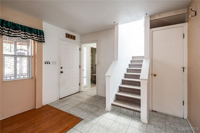 entrance foyer with light tile patterned floors and stairway