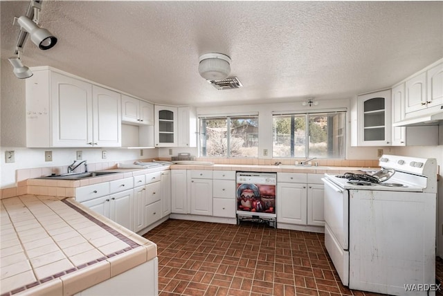 kitchen with white appliances, white cabinetry, glass insert cabinets, and tile counters