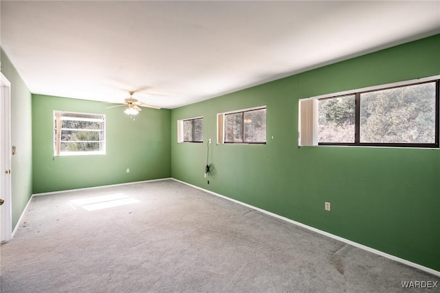 carpeted spare room featuring a ceiling fan and baseboards