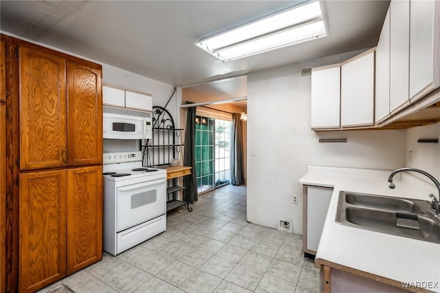 kitchen featuring light countertops, light tile patterned flooring, a sink, white cabinets, and white appliances