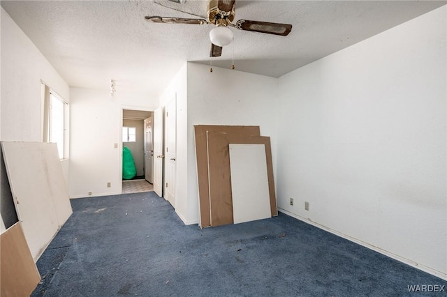 spare room featuring dark carpet, a textured ceiling, and ceiling fan