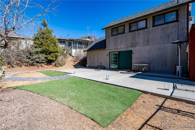rear view of house featuring a patio and a shingled roof