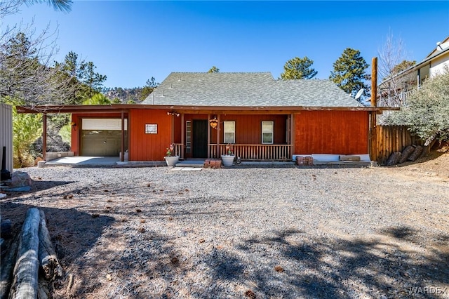 rustic home with a garage, covered porch, and roof with shingles