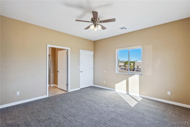 unfurnished bedroom featuring baseboards, visible vents, a ceiling fan, and light colored carpet